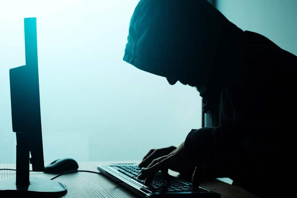 que es el hacking: un hacker encaputxat tecleja a l'ordinador